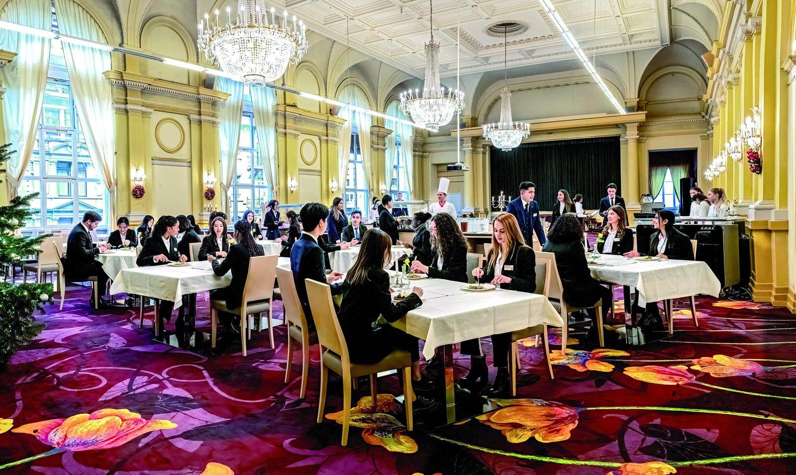 Students eating together under chandeliers in the BHMS dining hall