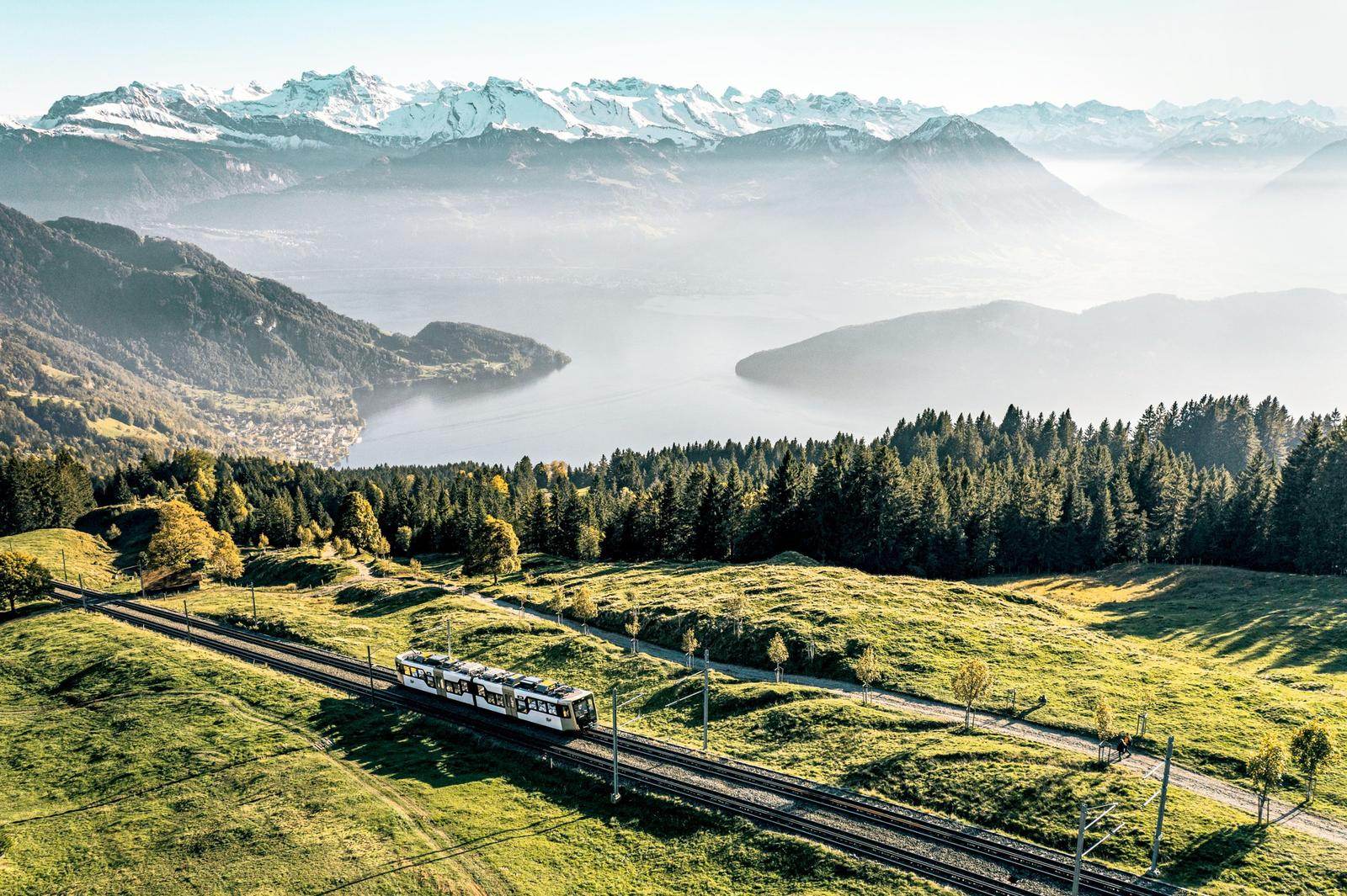 Rigi cogwheel railway climbing above Lake Lucerne with snow-capped Alps in the distance
